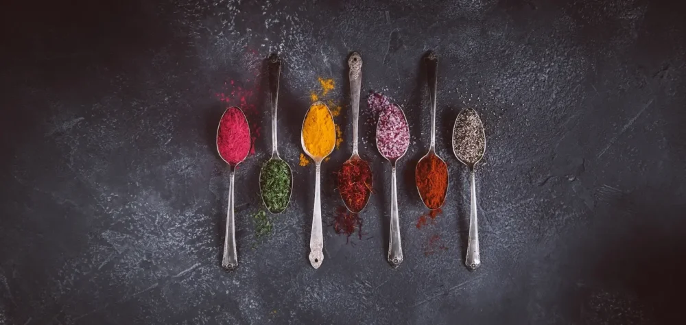 Spoons with spices on a grey background