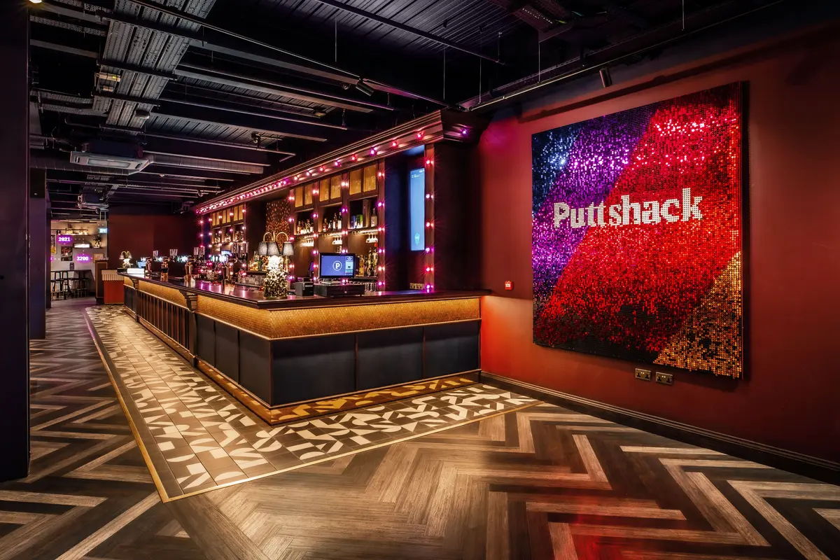 Puttshack Bar with a "Puttshack" blue, purple red, and gold artwork on display